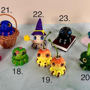 Pu&ograve; includere: Una collezione di figurine di polpo fatte a mano e stravaganti. Ogni polpo &egrave; progettato in modo unico con colori vivaci, glitter e vari accessori, tra cui un cappello da strega, una corona e un piccolo libro. Uno &egrave; in un cestino, un altro su un cuscino.