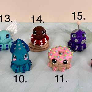 Pu&ograve; includere: Una collezione di figurine di polpo stravaganti, fatte a mano, in vari colori e design. Ogni figurina ha grandi occhi e caratteristiche uniche, tra cui ali, un fiocco e una forma a ciambella. Le figurine sono numerate da 9 a 16.