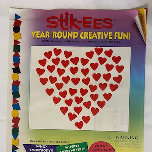 May include: A sheet of red heart-shaped reusable stickers that cling to surfaces like magic. The sheet is titled "Stik-Ees Year 'Round Creative Fun!" and includes instructions for use on various surfaces, including home, store windows, appliances, car windows, mirrors, ceramics, white boards, file cabinets, lockers, plastic containers, and bathtubs. The text also states that the stickers are not for children under 3 years old.