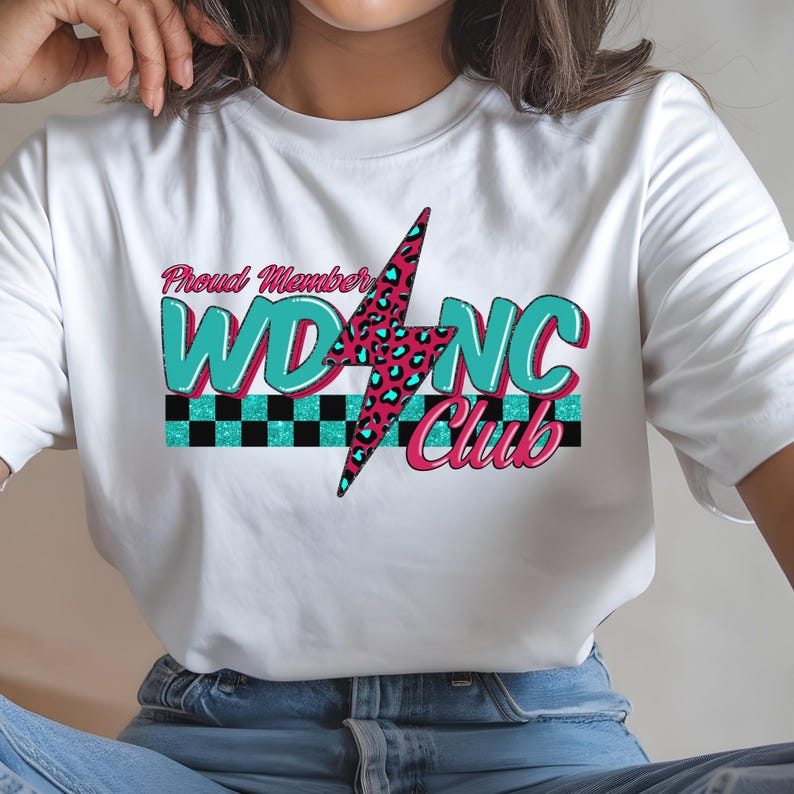 May include: White t-shirt featuring the text "Proud Member WDNC Club". The design includes a pink and teal lightning bolt with a leopard print pattern, teal letters, and a black and white checkered stripe.