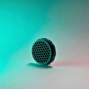 May include: A black honeycomb-shaped lens filter with a textured rim.