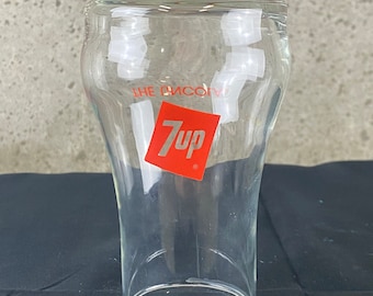 Può includere: Un bicchiere da bere in vetro trasparente 7 Up con un logo 7 Up rosso e le parole "The Uncola" stampate sul lato.