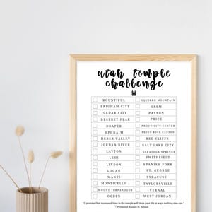 May include: A framed print with the words "Utah Temple Challenge" in a handwritten font. The print includes a checklist of Utah temple locations. A quote by President Russell M. Nelson is at the bottom. The frame is a light brown color.