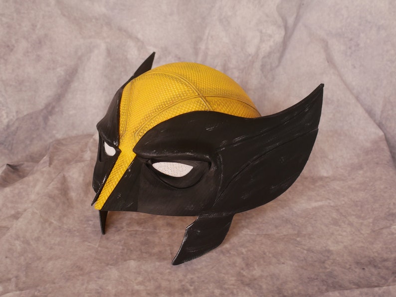 May include: A black and yellow plastic Wolverine mask with a textured yellow surface and black eye holes.