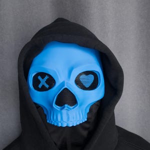 May include: A light blue skull mask with black mesh eye coverings and a black hood. The eye coverings have an X and a heart design. The mask is a costume accessory.