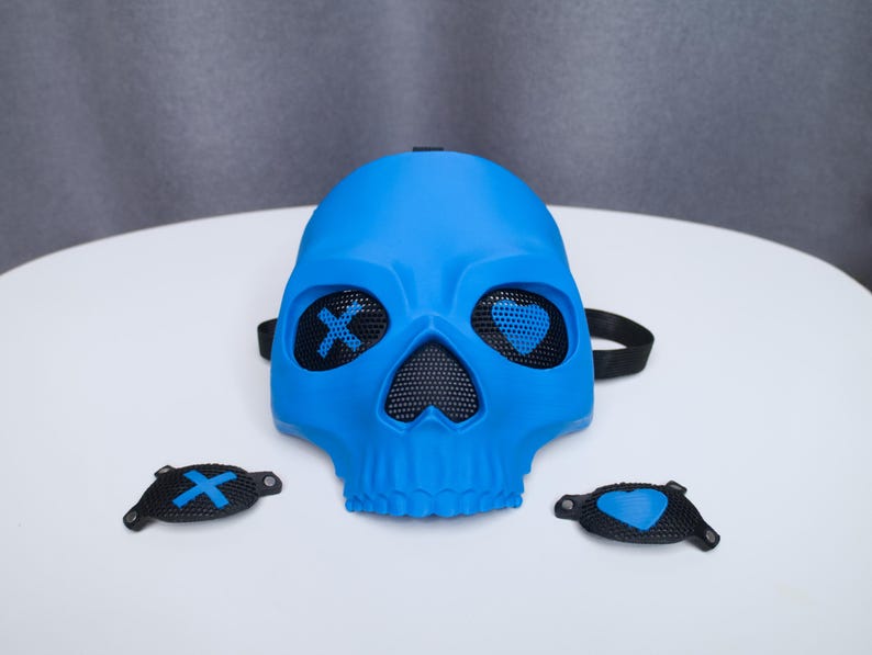 May include: A bright blue skull mask with mesh eye and nose openings. The eyes have an X and heart design. Two additional black eye covers with X and heart designs are included. The mask has a black strap.