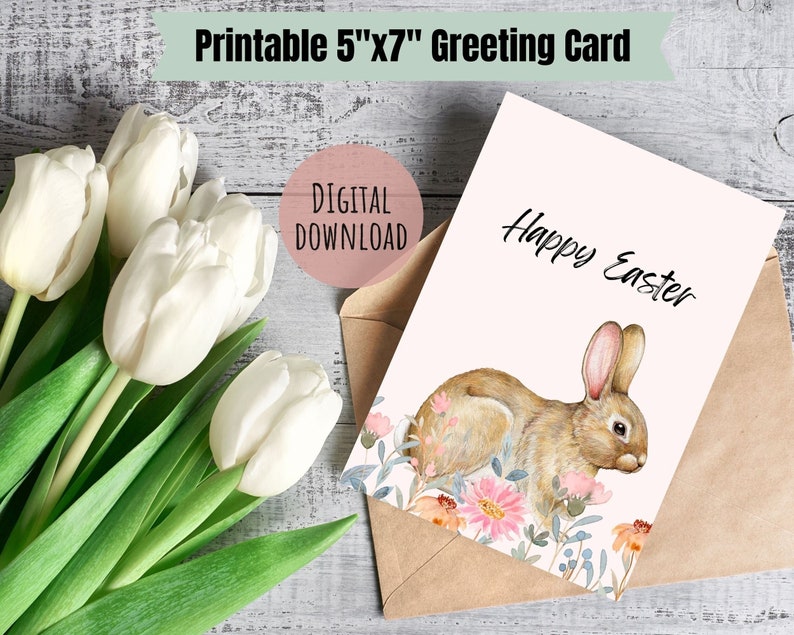 May include: Printable 5x7 inch greeting card featuring a watercolor illustration of a brown bunny rabbit in a field of pink and orange flowers. The card has the text "Happy Easter" written in black.