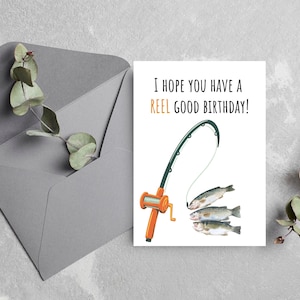 May include: A white card with a fishing rod and three fish on a line. The text on the card reads "I hope you have a REEL GOOD BIRTHDAY!"