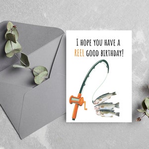 May include: A white card with a fishing rod and three fish on a line. The text on the card reads "I hope you have a REEL GOOD BIRTHDAY!"