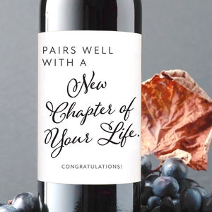 May include: A bottle of red wine with a white label that says "Pairs well with a New Chapter of Your Life. Congratulations!"