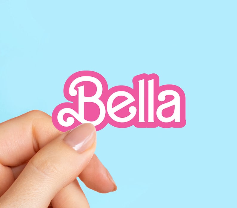 Może przedstawiać: R&oacute;żowa naklejka z napisem "Bella" napisanym białymi literami.