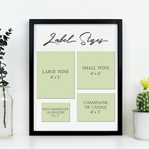 K&ouml;nnte beinhalten: Ein schwarzer Rahmen mit einer wei&szlig;en Tafel, auf der der Text "Label Sizes" in Kursivschrift steht. Die Tafel ist in vier Abschnitte unterteilt, die mit gr&uuml;nen Etiketten versehen sind, auf denen verschiedene Gr&ouml;&szlig;en f&uuml;r Wein-, Champagner- und Kerzen-Etiketten angegeben sind. Die Gr&ouml;&szlig;en sind in Zoll angegeben.