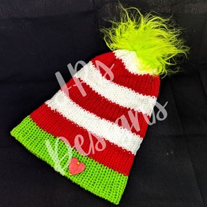 May include: Red and white striped knitted hat with a green pom-pom and a green brim. A red heart is attached to the brim.