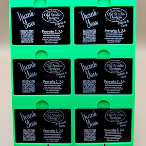 May include: A set of black cards with the words "Thank You" and a QR code, held in a bright green holder. Each card also features the text "Old Studio Designs" and a Bible verse.