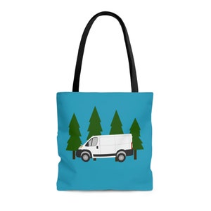 May include: A blue tote bag featuring a white van graphic in front of green pine trees. The bag has black handles and is made of a durable fabric. The design is simple and suitable for everyday use.