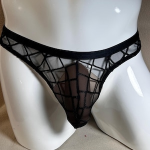 Könnte beinhalten: Schwarzer String-Tanga mit geometrischem Netzmuster. Die Unterwäsche besteht aus einem transparenten Material und hat einen tiefen Bund. Das Design ist ein klassischer Stil, geeignet für den Alltag.