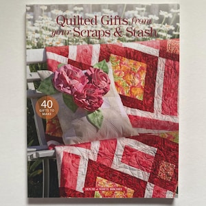 May include: A book cover titled "Quilted Gifts from your Scraps & Stash" featuring a red and white quilt with a floral pillow and pink fabric flowers. The cover also includes the text "40 Gifts to Make" and the publisher's name.