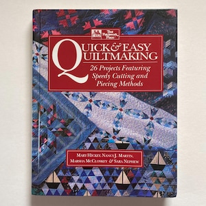May include: A book titled "Quick & Easy Quiltmaking" with a red banner and white text. The cover features a blue and red patchwork design. The book's authors are Mary Hickey, Nancy J. Martin, Marsha McCloskey & Sara Nephew.