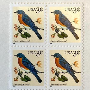 May include: Four US postage stamps featuring an illustration of an Eastern Bluebird perched on a branch with pink blossoms. Each stamp has the text "USA 3¢" and "Eastern Bluebird" with the year 1995 or 1996.