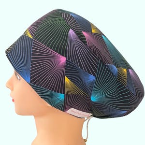 May include: A black scrub hat with a colourful geometric pattern of pink, blue, green, and yellow lines. The hat has a drawstring tie.