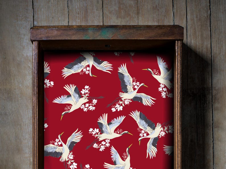 Fabric peel and stick drawer liner in a bold red background with elegant flying cranes and white cherry blossoms. This vintage-inspired contact paper adds a dramatic and artistic flair to any drawer, shelf, or cabinet. Ideal for kitchens, bathrooms, and antique furniture, the self-adhesive liner is easy to apply and remove. A perfect floral contact paper for those who love retro, Asian-inspired, or maximalist home décor. Stylish and functional for renters and homeowners alike.
