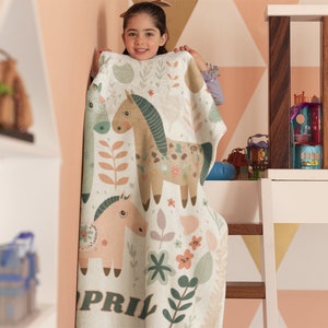 May include: A white and green blanket with a floral pattern and two horses. The blanket has the name "APRIL" printed on the bottom.