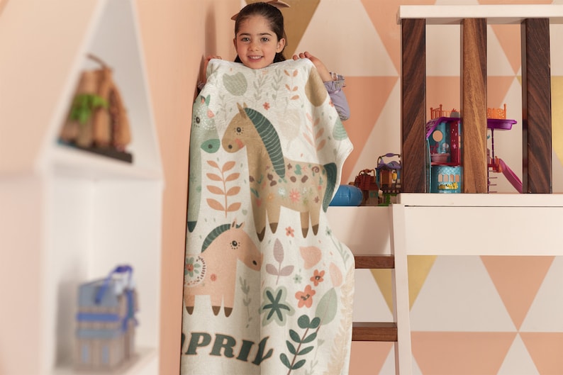 May include: A white and green blanket with a floral pattern and two horses. The blanket has the name "APRIL" printed on the bottom.