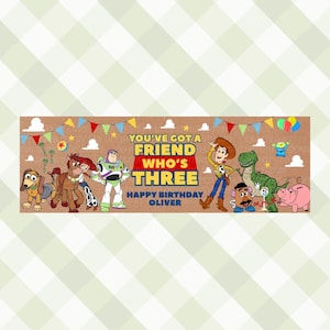 May include: A rectangular birthday banner featuring Toy Story characters including Woody, Buzz Lightyear, Jessie, Rex, and Slinky Dog. The text reads YOU'VE GOT A FRIEND WHO'S THREE HAPPY BIRTHDAY OLIVER against a brown background with clouds.