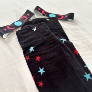May include: A pair of black knee-high socks with red and blue stars. The socks have a small paw print charm on the top.