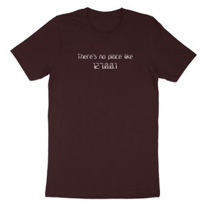 Op de afbeelding: Een maroon t-shirt met de tekst "There's no place like 127.0.0.1" in wit gedrukt.