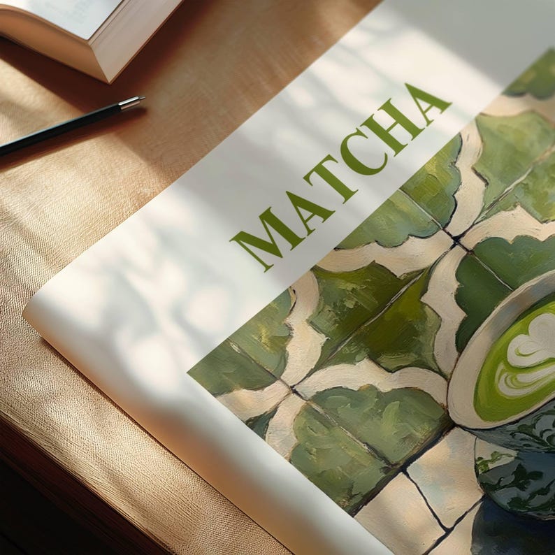 May include: A close-up of a magazine cover with the word "MATCHA" printed in green letters. The background is a green and white tiled pattern with a cup of green tea with latte art on top of the tiles.