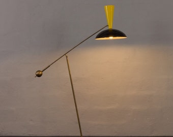 May include: A brass floor lamp with a black and yellow shade. The lamp has a long, adjustable arm and a round base.