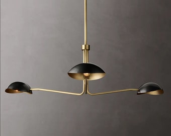 May include: A three-light gold pendant light fixture with black metal shades. The shades are angled and have a rounded shape. The fixture has a long, straight arm that extends from the center shade to the two side shades.