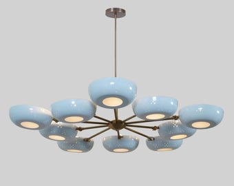 May include: A modern chandelier with a bronze finish and ten light blue, bowl-shaped shades. Each shade has a speckled pattern and emits a warm glow. The fixture is suspended from a matching bronze ceiling mount.