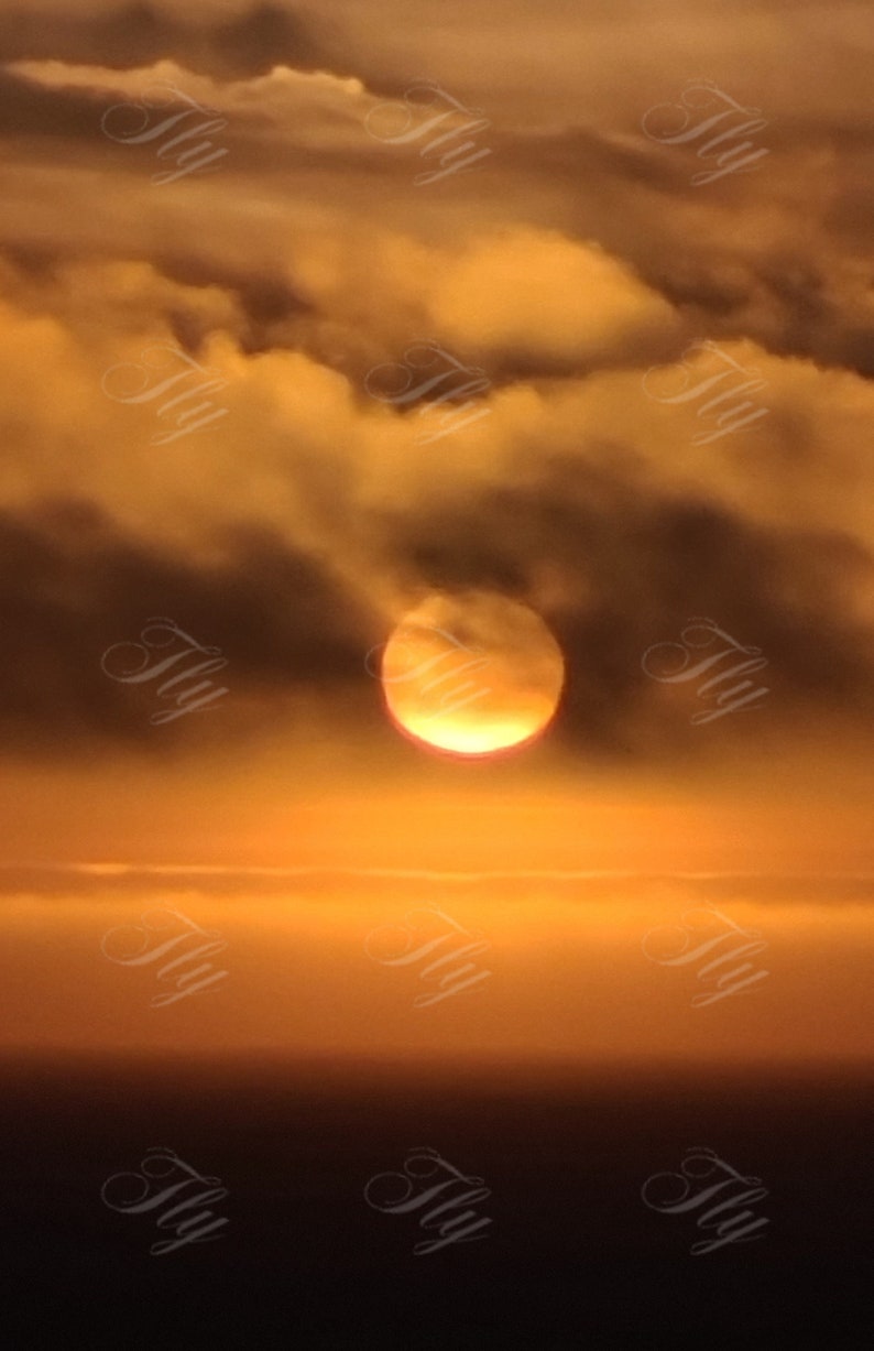 K&ouml;nnte beinhalten: Ein leuchtend orangefarbener Sonnenuntergang mit flauschigen Wolken am Himmel. Die Sonne geht hinter den Wolken unter und erzeugt einen warmen Schein.