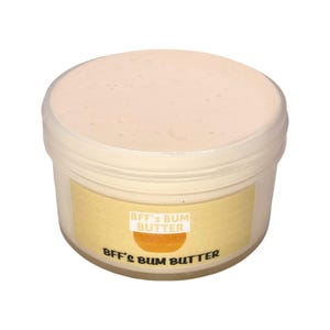 May include: A white plastic jar with a yellow label that reads "BFF's Bum Butter". The jar is filled with a light pink cream.