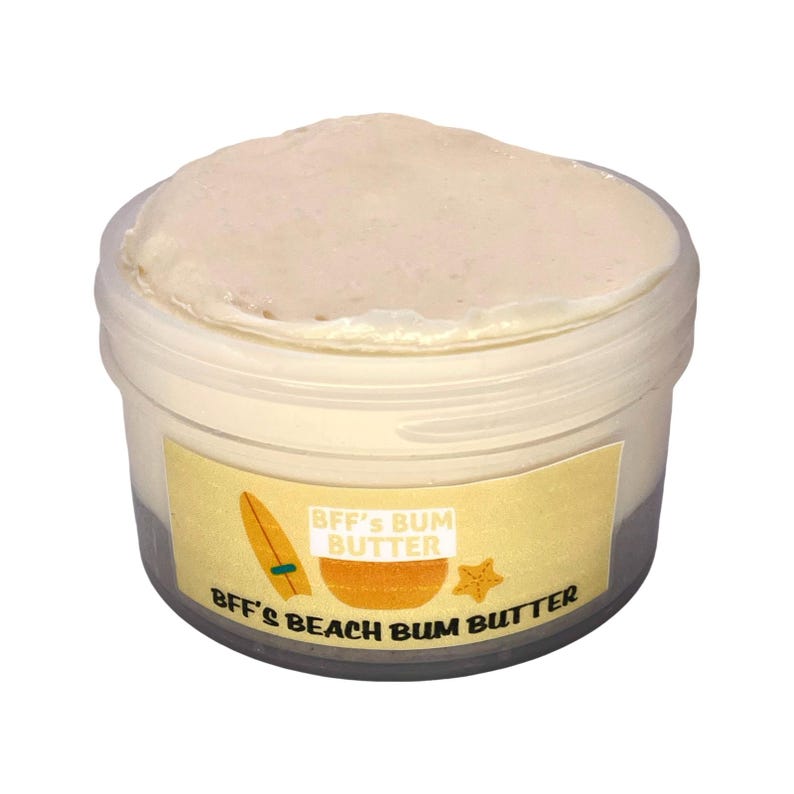 Pu&ograve; includere: Un piccolo barattolo di plastica trasparente riempito con una crema beige chiaro. Il barattolo ha un'etichetta gialla con il testo "BFF's Bum Butter" e grafiche a tema spiaggia. La crema ha un aspetto liscio e leggermente strutturato.