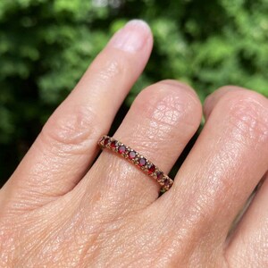 Könnte beinhalten: Ein Goldring mit einer Reihe kleiner, roter Edelsteine.