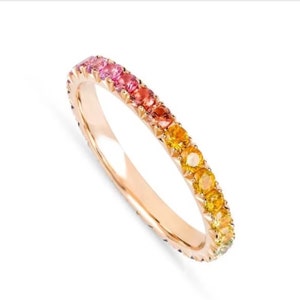Könnte beinhalten: Ein zarter Goldring mit einem Regenbogen aus Saphiren, die in einem abgestuften Muster gesetzt sind. Der Ring ist aus 14 Karat Roségold gefertigt und verfügt über insgesamt 20 Saphire.