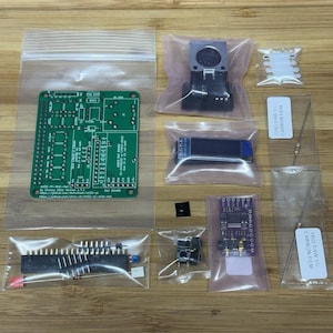 May include: An electronic component kit featuring a green printed circuit board labeled mt32-pi-Midi-Hat, a black MIDI port, a small blue display module, a purple breakout board, various resistors with labels, and assorted pins in clear plastic bags.