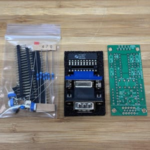 May include: An electronic component kit containing a clear plastic bag with resistors labeled 470, a black foam block holding a blue and silver VGA connector with a P174FCT 245TPC chip, and a green rectangular printed circuit board with white text.