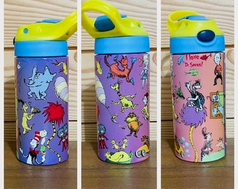 Peut inclure: Trois bouteilles d'eau en acier inoxydable avec des motifs de personnages de Dr. Seuss colorés. Les bouteilles ont un fond violet, rose et bleu clair avec des couvercles jaunes et des dessus bleus. Le texte sur la bouteille rose indique "J'aime Dr. Seuss !"