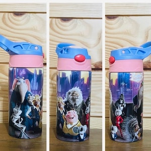 May include: A pink and blue water bottle with a flip top lid. The bottle features a colorful graphic of characters from the animated movie Sing 2. The characters include a pig, a koala, a gorilla, and an elephant.