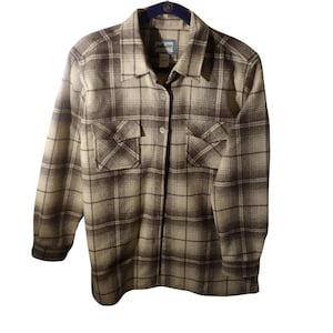May include: A button-down, long-sleeve plaid shirt in shades of brown and cream. The shirt features two chest pockets and a collared neckline. The label reads "Pendleton".