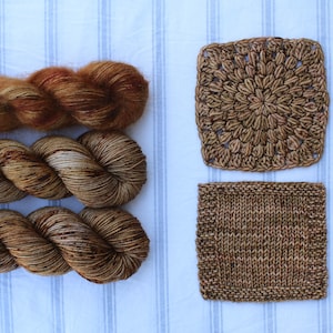 Puede incluir: Tres ovillos de hilo marrón y naranja con un cuadrado de ganchillo y un cuadrado de punto.