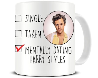 May include: White ceramic mug with a black check box and the text "Mentally dating Harry Styles" checked. The other two check boxes are unchecked and say "Single" and "Taken". A photo of Harry Styles is in the background.