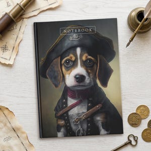 May include: A rectangular notebook with a black cover featuring a beagle puppy dressed as a pirate, wearing a black tricorn hat and a dark coat with a red scarf. The word NOTEBOOK is printed in white at the top center of the cover design.
