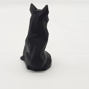 May include: A black geometric wolf sculpture. The wolf is sitting with its tail tucked between its legs. The sculpture is made of a smooth, black material.