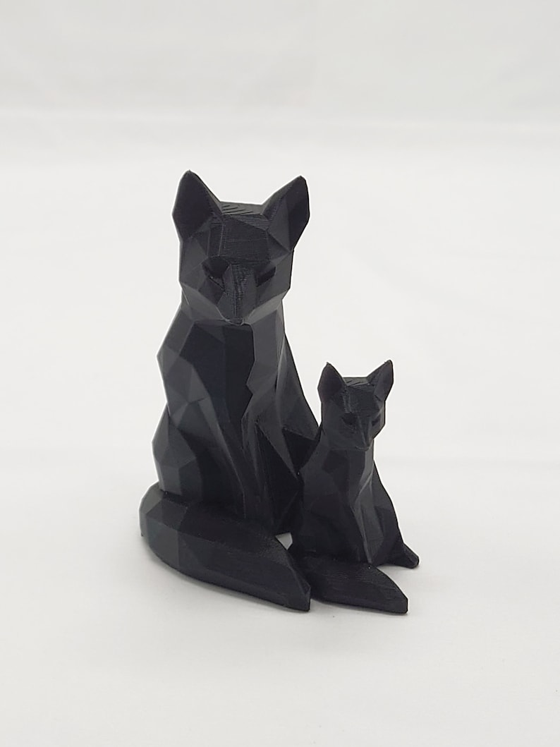 May include: A black, geometrically designed fox figurine with a smaller fox figurine sitting beside it.