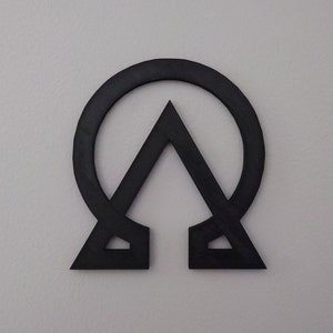 May include: A black metal wall decor in the shape of a circle with a triangle inside. The circle is open at the top and bottom, and the triangle is pointing upwards.